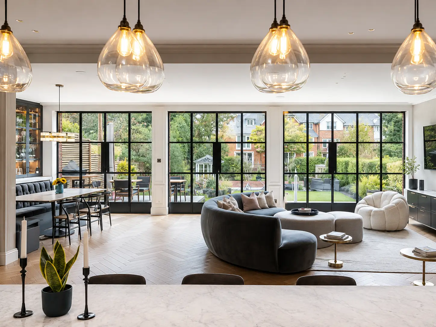 Crittall French doors with black steel frames across a bright open-plan living room overlooking a landscaped garden